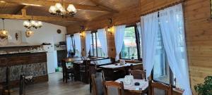 a dining room with tables and chairs and windows at Къща за гости Деметра in Velingrad