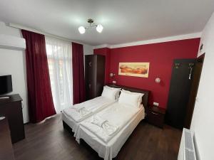 a bedroom with a white bed in a red wall at Къща за гости Деметра in Velingrad