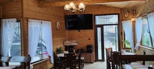 a dining room with tables and a television on the wall at Къща за гости Деметра in Velingrad