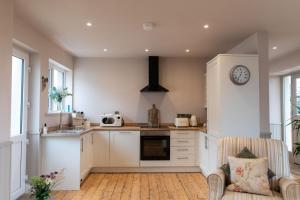 a kitchen with white cabinets and a clock on the wall at Lough View Cottage in Killinchy