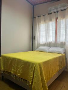 a bedroom with a yellow bed with a window at Suíte da Alê in Marau