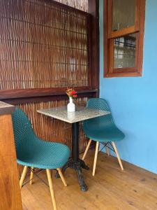 a table with two chairs and a vase of flowers on it at Suíte da Alê in Marau