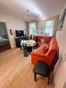 Fewo Warnemünde في روستوك: غرفة معيشة مع أريكة حمراء وطاولة