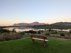 a bench sitting on the grass with a view of a lake at Lauvåsstua-Charming house by the sea in Bøstad