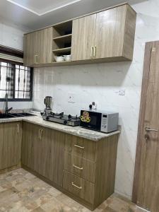 una cocina con armarios de madera y microondas en una encimera en Viklis Luxury Apartments, en Port Harcourt