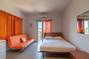Voula Apartments في ميتيكاس: غرفة نوم بها سرير وكرسي برتقالي