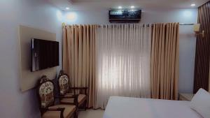 Comfort Lodge في كراتشي: غرفة نوم بسرير وكرسيين وتلفزيون