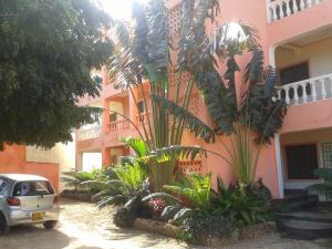 a car parked in front of a pink building with plants at The TrueNorth apartments of diani in Diani Beach