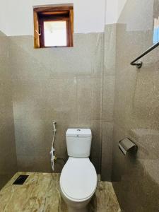 a bathroom with a white toilet and a window at Brampy Guest in Polonnaruwa