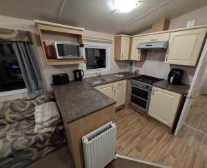 a small kitchen with a couch in a caravan at Stay static Hayling island holiday park in South Hayling