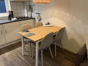 a dining room table with chairs and a kitchen at Zomerhuis Zwart in Egmond aan Zee