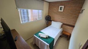 ブルマジーニョにあるCasa de Nair Pousadaのレンガの壁の小さなベッドルーム(ベッド1台付)