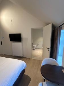una camera da letto con un letto, un tavolo e una TV di Manteka Logies a Ypres