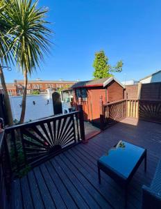 a deck with a bench and a tree and a building at Three Bees in Hythe