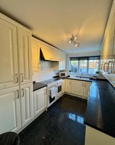 a large kitchen with white cabinets and black counter tops at Three Bees in Hythe +9 photos