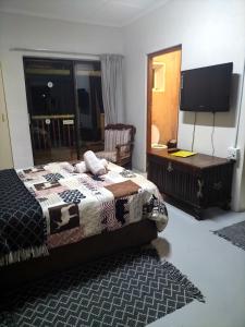 a bedroom with a bed and a desk and a television at Cango's Rest in Oudtshoorn