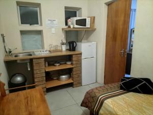a small kitchen with a sink and a refrigerator at Cango's Rest in Oudtshoorn