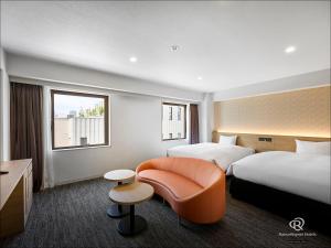 a hotel room with two beds and a chair at Daiwa Roynet Utsunomiya in Utsunomiya