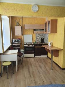 a small kitchen with a stove and a clock on the wall at Apartament Erfolg 3 in Daugavpils
