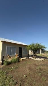 a house with a tree in front of it at Cabaña en General Acha in General Acha