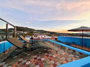 a balcony with a chair and an umbrella on a building at Authentic Dual Terrace house in Chefchaouene