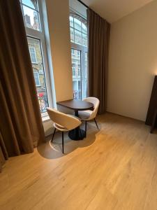 a room with a table and two chairs and two windows at Manteka Logies in Ieper