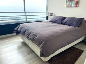 a large bed in a room with a large window at Departamento arriendo remodelado in Viña del Mar