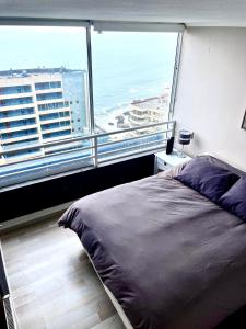 a bedroom with a bed and a large window at Departamento arriendo remodelado in Viña del Mar
