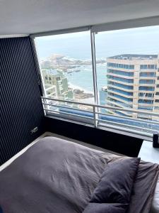 a bedroom with a bed in front of a large window at Departamento arriendo remodelado in Viña del Mar