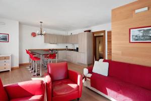 a living room with a red couch and red chairs at Sunny Arabba Apartment in Arabba