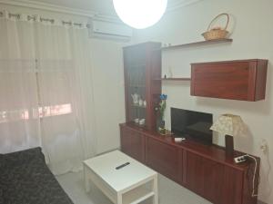 Una sala de estar con un televisor y una mesa. en Confortable piso en Puertollano, en Puertollano