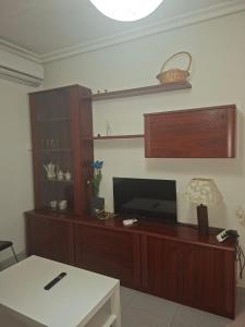 una sala de estar con un centro de entretenimiento con TV de pantalla plana en Confortable piso en Puertollano, en Puertollano 8 fotos más