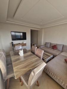 apartement avec piscine résidence sécurisée meublé confort jnan dalia Boznika في بن سليمان: غرفة معيشة مع طاولة خشبية وأريكة