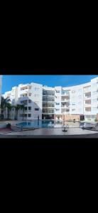 apartement avec piscine résidence sécurisée meublé confort jnan dalia Boznika في بن سليمان: مبنى أبيض كبير أمامه مقعد