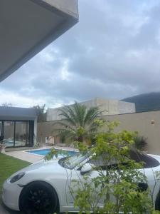 una macchina bianca parcheggiata di fronte a una casa di Enseada Beach a São Sebastião