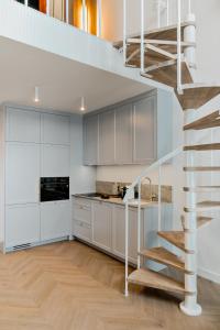 a kitchen with white cabinets and a spiral staircase at Zegrze Lake Apartament przy Narwi LEKKO z sauną in Zegrze
