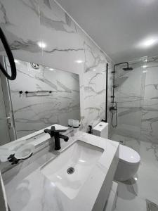 a white bathroom with a sink and a toilet at Wadi Rum Bubbles Wissam camp in Wadi Rum