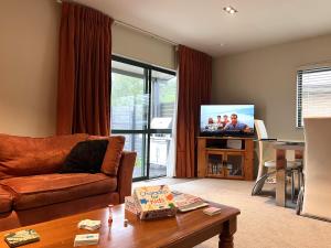 a living room with a couch and a flat screen tv at A family friendly haven in Hanmer Springs