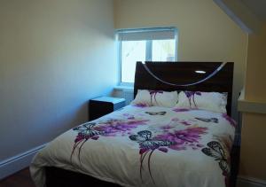 a bedroom with a bed with a floral bedspread at SS Sunrise & Silk in Bognor Regis