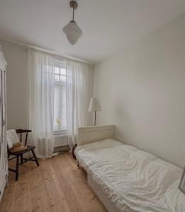 a white bedroom with a bed and a window at Romantische kamer nabij centrum in Eindhoven