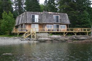 a house on a dock next to a body of water at Everett Cottage at Indian Point in Bar Harbor in Bar Harbor