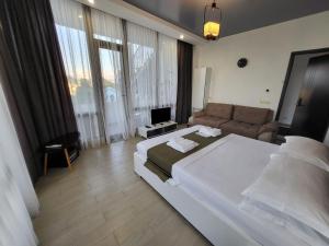 a bedroom with a large white bed and a couch at Hotel SABA in K'obulet'i