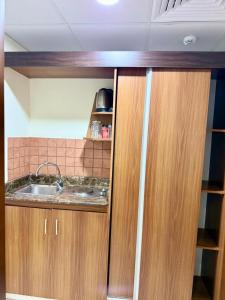 a kitchen with wooden cabinets and a sink at Mizab Hotel From Nebras Alhuda in An Naqāʼ