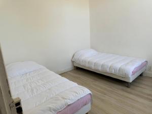 two beds in a room with white walls and wood floors at Montluçon Centre ville maison in Montluçon +5 photos