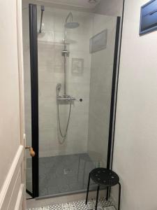 eine Duschkabine mit einem schwarzen Hocker in einem Badezimmer in der Unterkunft Chambre à la campagne in Québriac