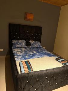 a bed with a blue comforter and pillows on it at Cutting Edge Guest House in Daranka