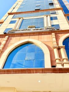 a tall building with blue glass windows on it at Mizab Hotel From Nebras Alhuda in An Naqāʼ