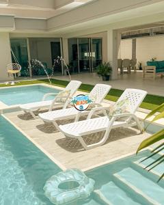 Un grupo de sillas junto a una piscina. en Sun Beach, en Puerto Colombia