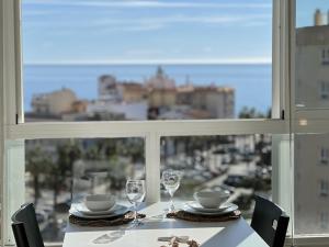 a table with glasses and plates and a view of a city at Despierta cerca del Mar,con la Playa a un paso!! Carabela-C704 Piscina Torrox-Costa in Torrox Costa