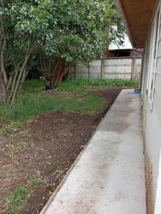 a concrete sidewalk next to a yard with a fence at Cabaña interior en el centro de llanquihue in Llanquihue